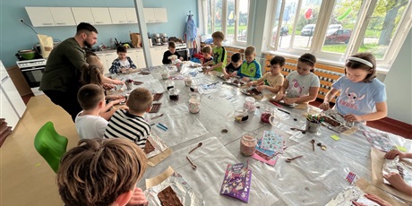 Powiększ grafikę: Dzieci pakują czekoladę w przygotowane opakowania.