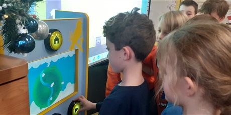Powiększ grafikę: Chłopiec z klasy 1c gra na automacie gier. 