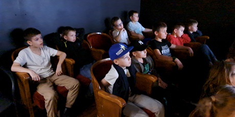 Powiększ grafikę: Grupa dzieci siedzi w fotelach i ogląda film pt. "Średniowieczne zawody".