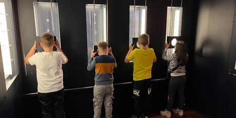 Powiększ grafikę: Uczniowie klasy 2b przez szkło powiększające oglądają zgromadzone okazy muzealne.
