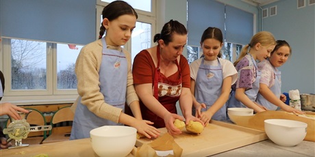 Powiększ grafikę: Cztery dziewczynki z panią przygotowują ciasto do wałkowania.