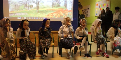 Powiększ grafikę: Grupa dziewczynek w chustach na głowie siedzi z podpartą brodą na krzesełkach.
