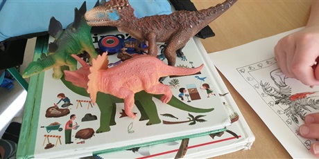Powiększ grafikę: Uczniowie oglądają figurki dinozaurów