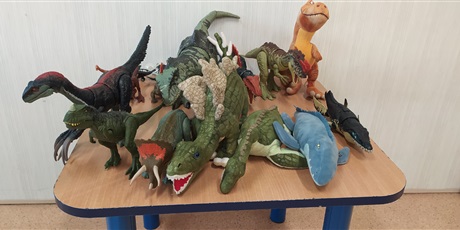 Powiększ grafikę: na stoliku stoją różne figurki z dinozaurami