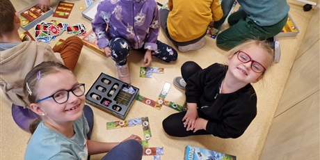 Powiększ grafikę: trzy dziewczynki siedzą na podłodze i grają w grę planszową