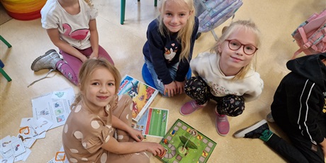 Powiększ grafikę: cztery dziewczynki siedzą na podłodze i grają w grę planszową