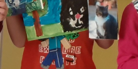 Powiększ grafikę: Chłopiec z 1c przedstawia swoje prace plastyczne przedstawiające koty.
