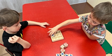 Powiększ grafikę: Dwoje dzieci przy stoliku gra w kółko i krzyżyk