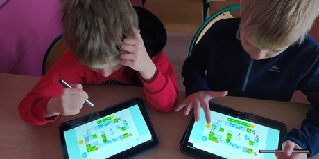 Powiększ grafikę: Dwoje uczniów koduje klocki Lego na tablecie.