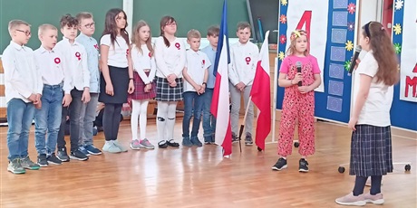 Powiększ grafikę: Grupa dzieci trzyma w rękach flagi Polski i UE. Dwie dziewczynki trzymają w ręku mikrofon.