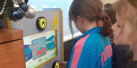 Powiększ grafikę: Dziewczynka z klasy 1c gra na automacie gier. 