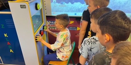 Powiększ grafikę: Chłopcy z kl.2b obserwują kolegę grającego na automacie do gier.