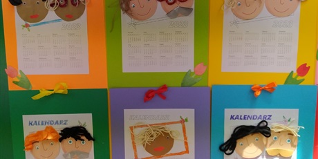 Powiększ grafikę: Na stole leżą kolorowe kartki z przyklejonymi rysunkami twarzy i kalendarzem.