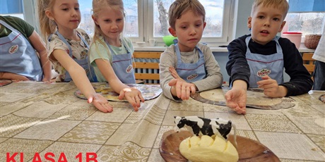 Powiększ grafikę: Czworo dzieci wskazuje dłonią na położone masło.
