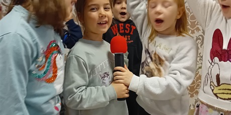 Powiększ grafikę: Trzy dziewczynki śpiewają trzymając w dłoniach mikrofon.