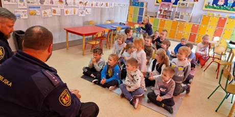 Powiększ grafikę: Dzieci siędzą na podłodze i słuchają opowieści strażników