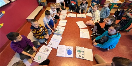 Powiększ grafikę: Dzieci siedzą na podłodze i prezentują zgromadzone materiały o Antarktydzie.