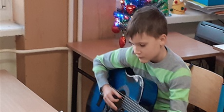 Powiększ grafikę: uczeń klasy 2a gra kolędę na gitarze przy choince