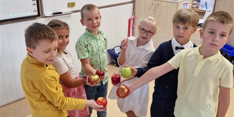 Powiększ grafikę: dzieci stoją w kółku i trzymają w dłoni jabłka