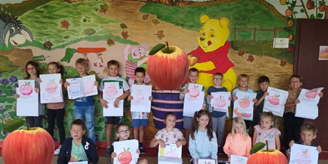 Powiększ grafikę: Dzieci ze swoimi odkodowanymi jabłkami stoją w towarzystwie Kubusia Puchatka i wielkich jabłek
