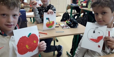 Powiększ grafikę: Dzieci siedzą przy stolikach i pokazują wykonane prace plastyczne z plasteliny na których jest plastelinowe jabłko.