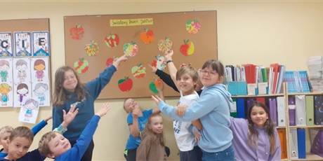 Powiększ grafikę:  Dzieci pokazują wykonane przez siebie wydzieranki jabłek, które umieszczone są na tablicy w klasie.
