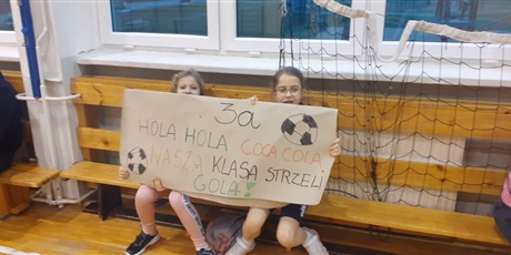 Powiększ grafikę: Dziewczynki trzymają transparent zagrzewający do gry piłkarzy z klasy 3a.