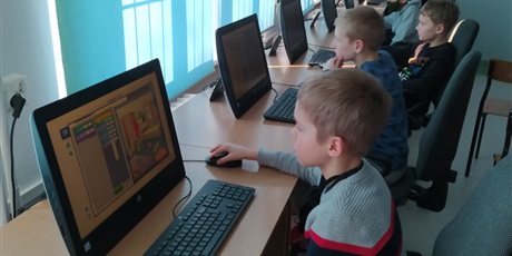 Powiększ grafikę: Pięciu chłopców siedzi i patrzą na ekran monitora.