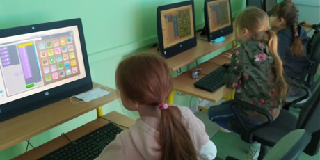 Powiększ grafikę: Trzy dziewczynki siedzą i patrzą na ekran monitora.