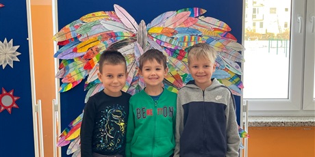 Powiększ grafikę: Troje uczniów stoi na tle kolorowych skrzydeł.