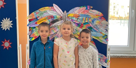 Powiększ grafikę: Troje dzieci stoi na tle kolorowych skrzydeł.