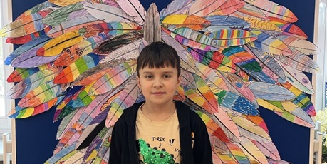Powiększ grafikę: Chłopiec stoi na tle kolorowych skrzydeł.