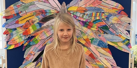 Powiększ grafikę: Dziewczynka stoi na tle kolorowych skrzydeł.