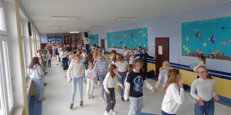 Powiększ grafikę: Duża grupa uczniów tańczy podczas przerwy na holu.
