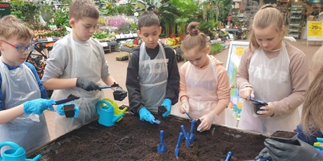 Powiększ grafikę: Chłopcy i dziewczynki sadzą nasionka kwiatów.