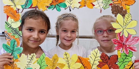 Powiększ grafikę: trzy dziewczynki trzymają w ręku fotobudkę z jesiennych liści