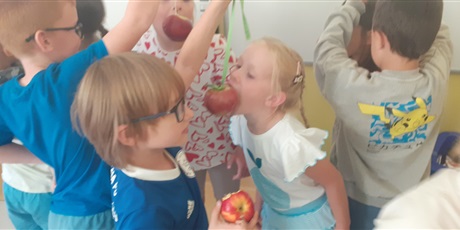 Powiększ grafikę: Dzieci jedzą jabłka bez użycia rąk. 