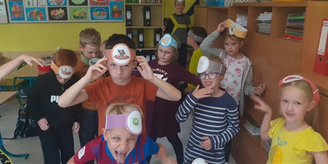 Powiększ grafikę: Dzieci mają na głowach opaski z ilustracją zwierzątek polnych, wesoło ilustrują ruchem treść opowiadania czytanego przez nauczyciela.