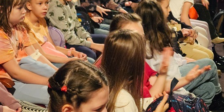 Powiększ grafikę: Grupa dzieci siedząca na widowni teatru.